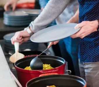 Kollegaer forsyner seg med et varmt måltid fra en lunsjbuffet